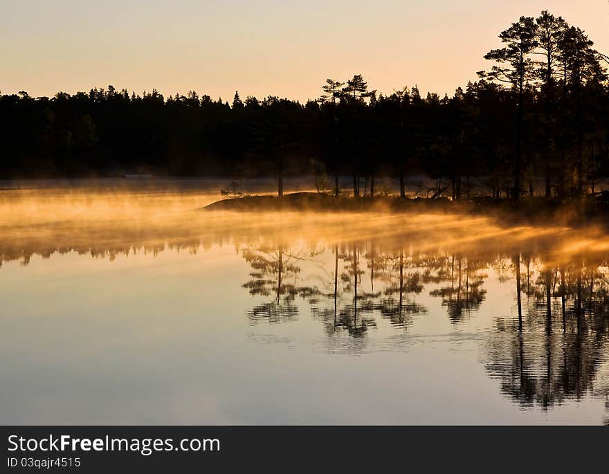 Morning haze over the lake, sunlit through the trees. Morning haze over the lake, sunlit through the trees.