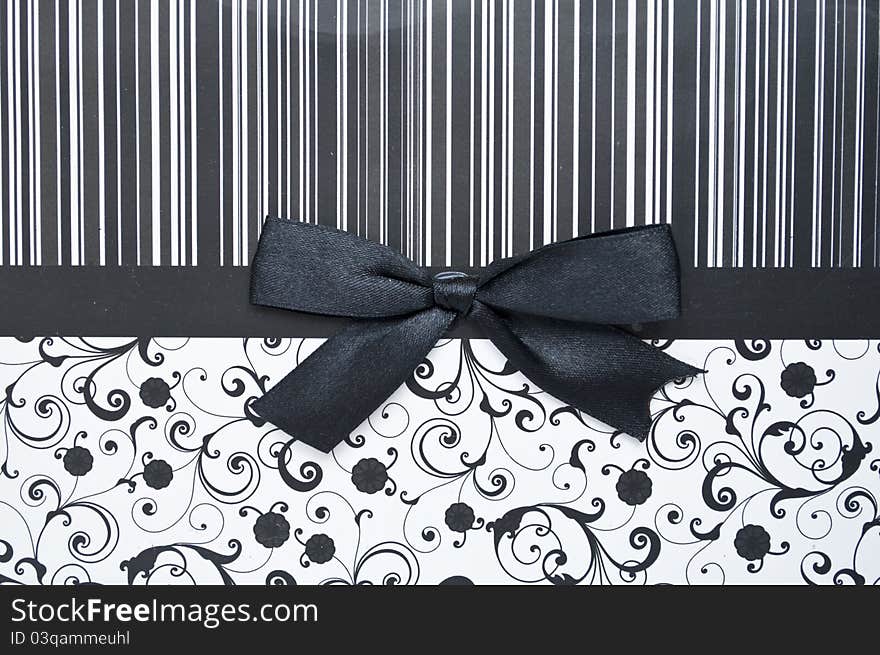 Black gift bow on black seamless pattern - background for shopping concept