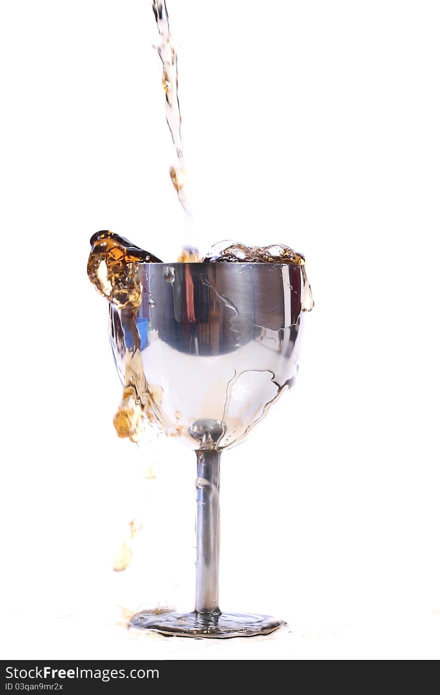 Pouring drink in metal glass isolated on white background