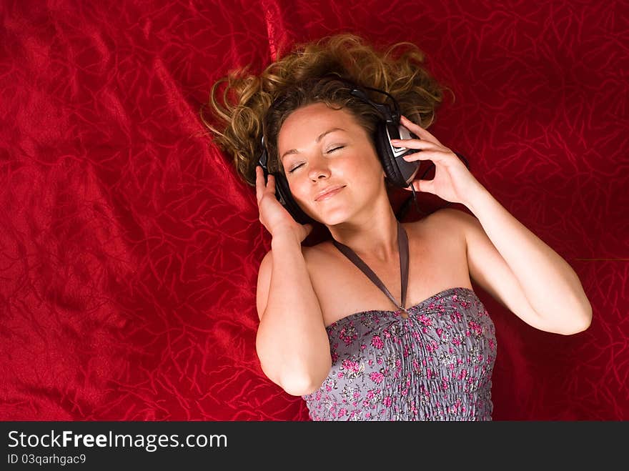 Cute girl with headphones on red bed. Cute girl with headphones on red bed