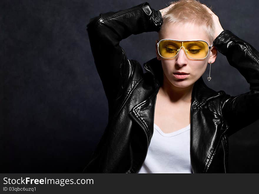 The young girl in a leather jacket and yellow glasses