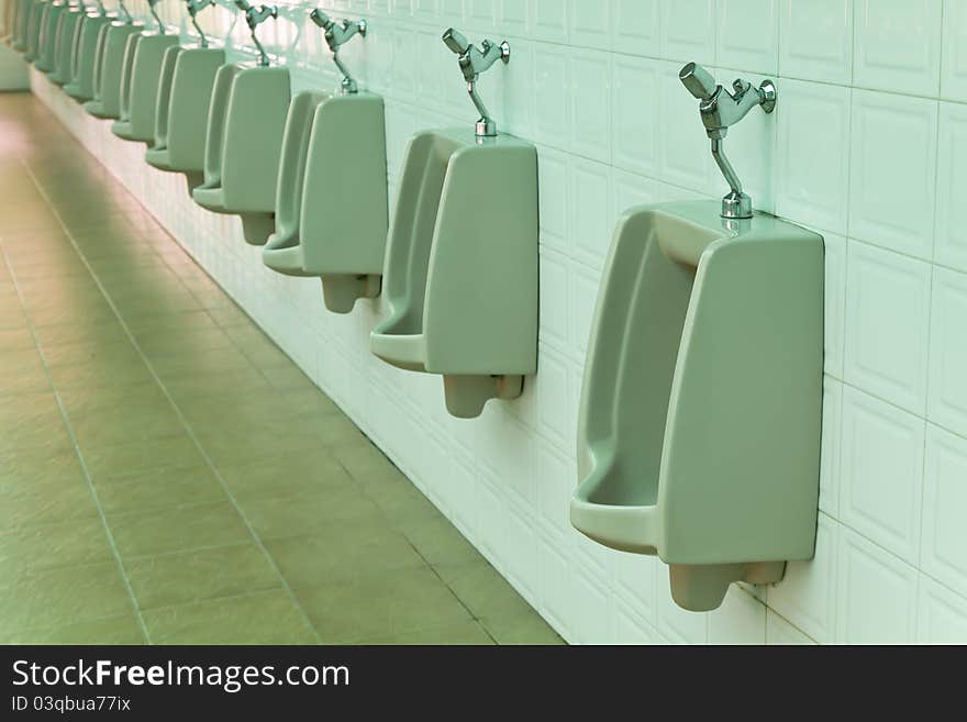 A row of urinals in tiled wall in a public restroom