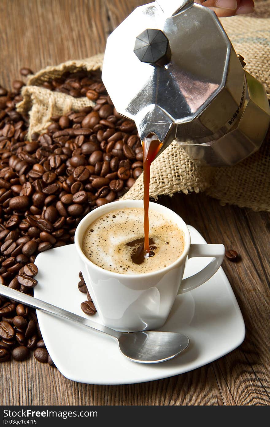 Coffee cup with burlap sack of roasted beans on rustic table