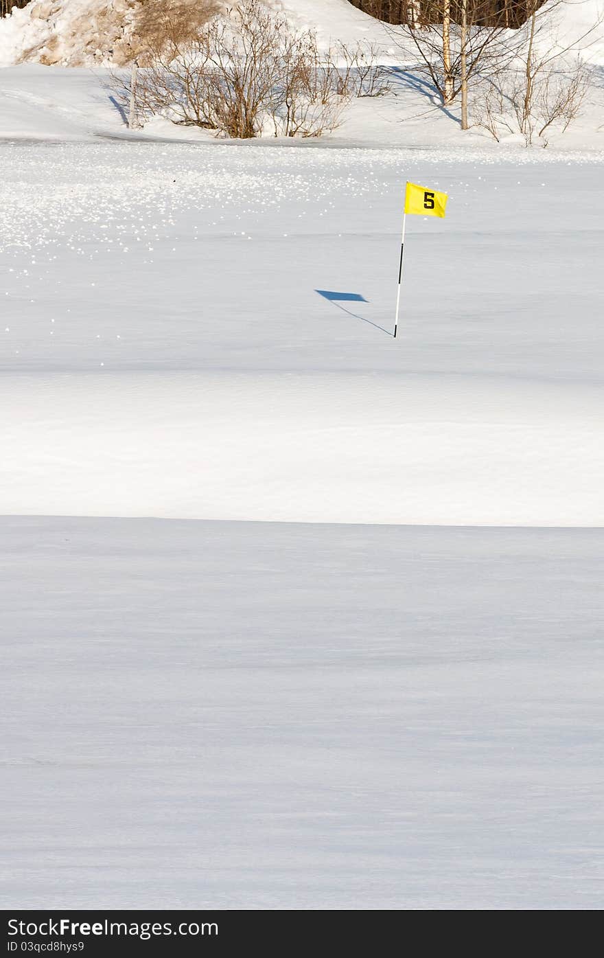 A golf green covered in snow with the sand bunker visible in front. A golf green covered in snow with the sand bunker visible in front.