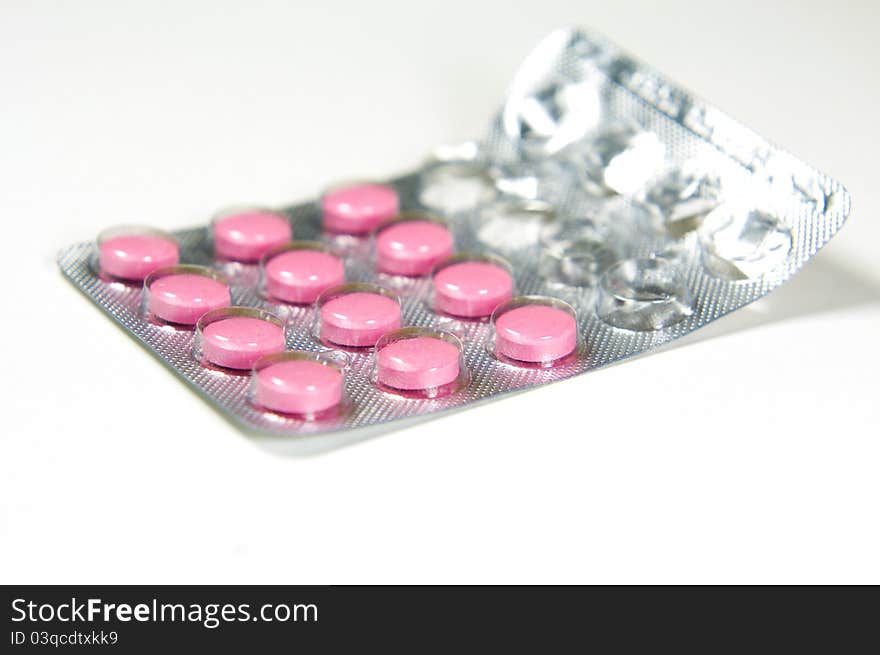 Package of pink tablets on white background