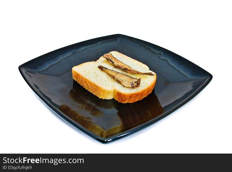 Square black plate with bread and sprats. Isolated on white background