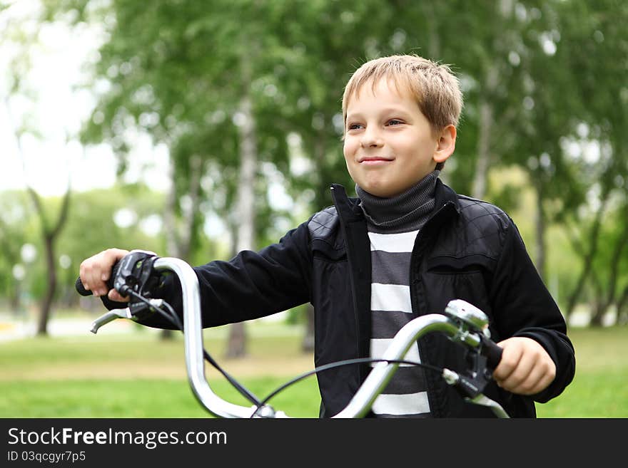 Happy smiling boy on a bicycle in the green park