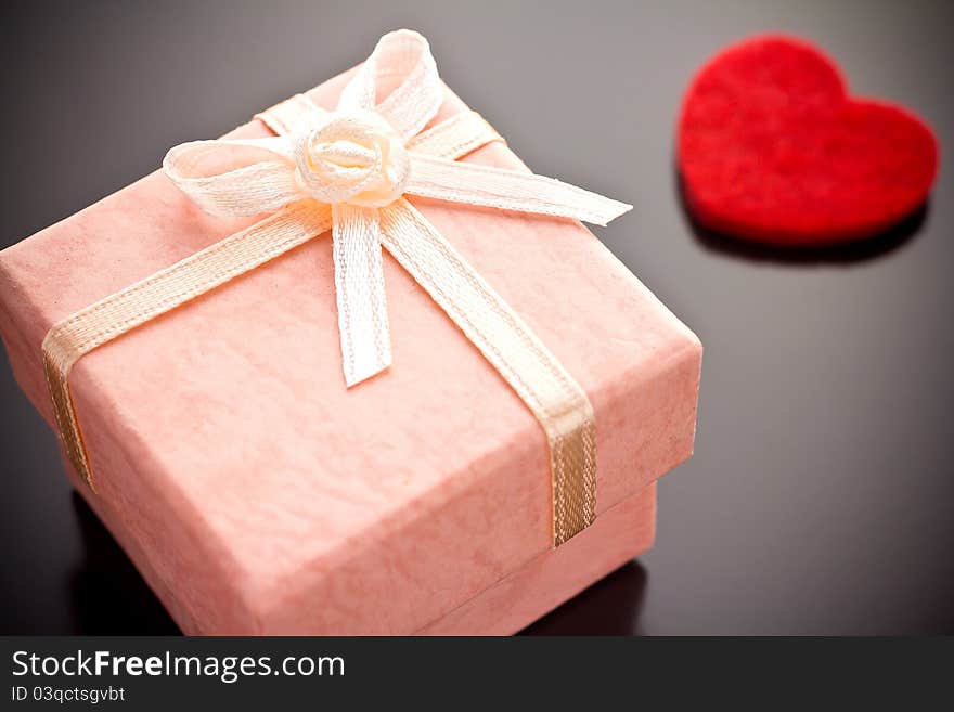 Pink gift box with a red heart on a gray background. Pink gift box with a red heart on a gray background.