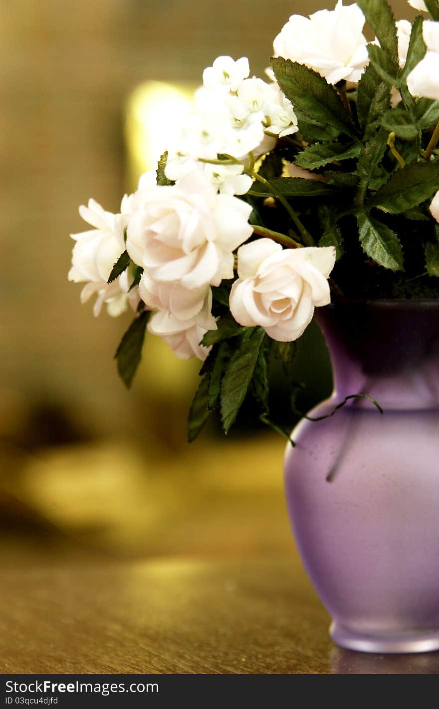 Silk flowers sitting in purple vase on table. Silk flowers sitting in purple vase on table