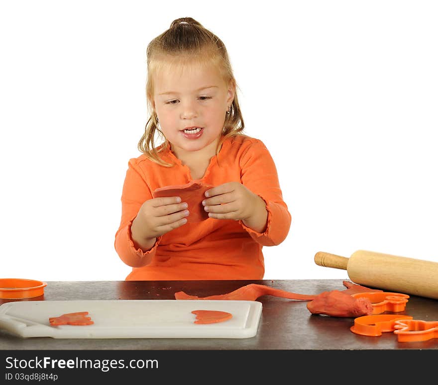 A cute preschooler making Halloween cutouts using modeling clay, a rolling pin and cookie cutters. A cute preschooler making Halloween cutouts using modeling clay, a rolling pin and cookie cutters.