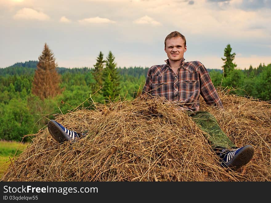 Young man astride hay stack. Young man astride hay stack