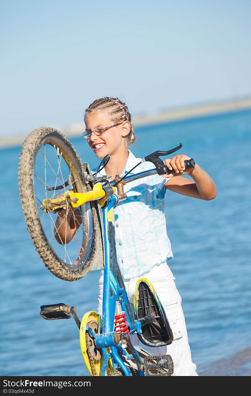 Beautiful young girl standing with her bicycle. the background sea