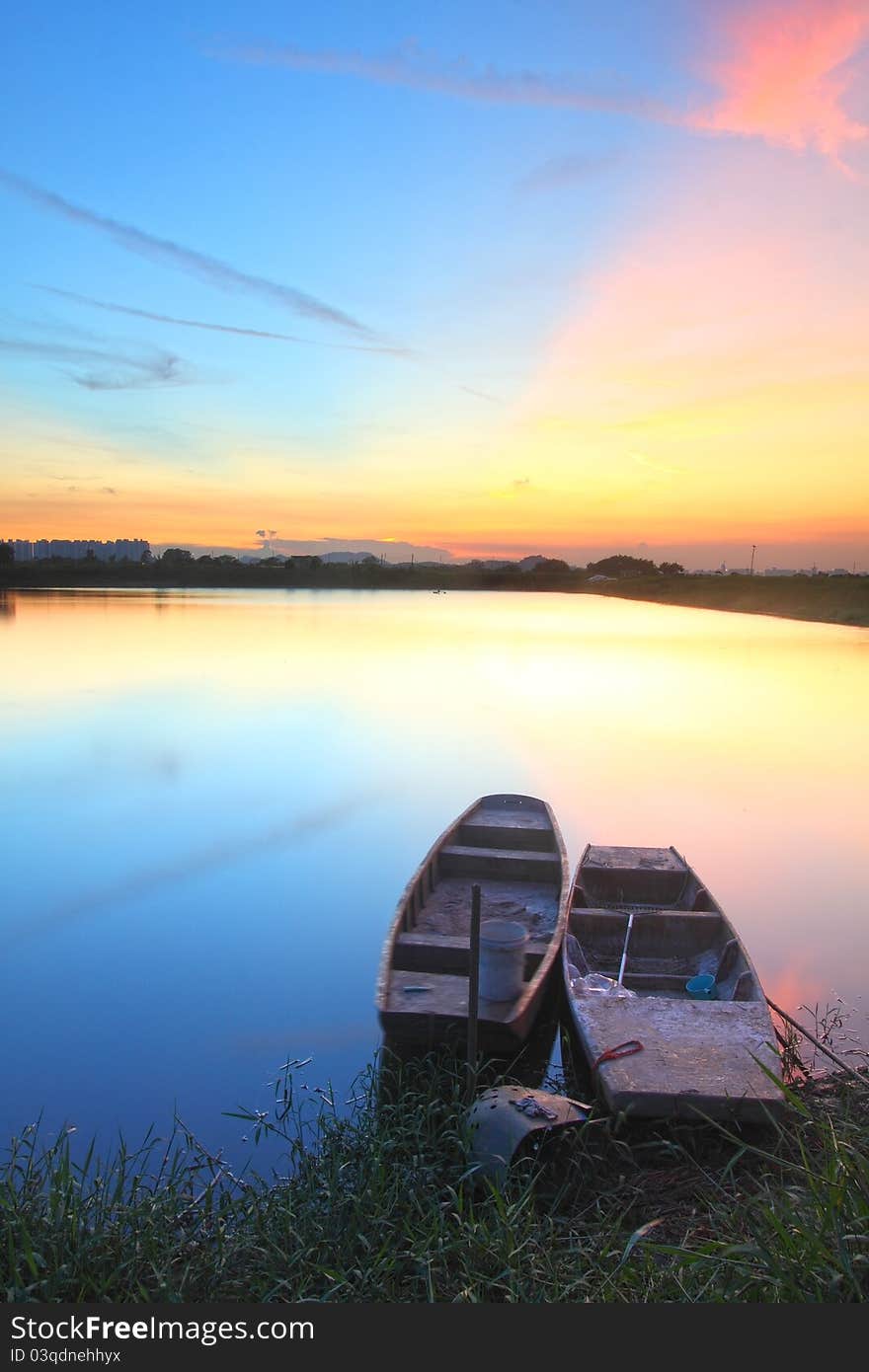 Sunset with isolated boats in water body