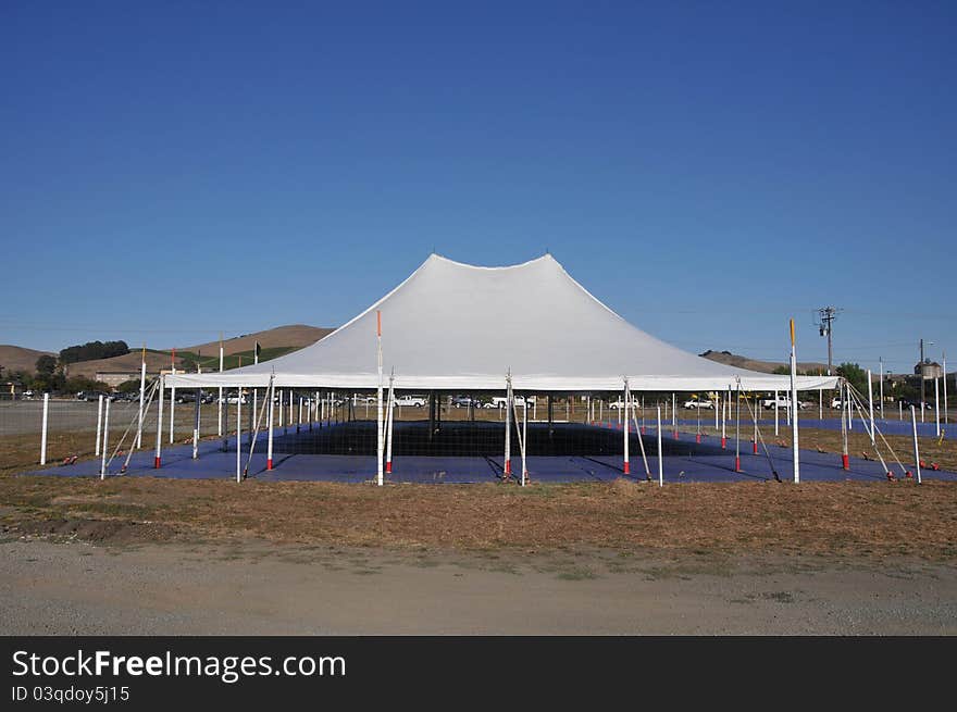 A white tent covers an empty space with hills in the background. A white tent covers an empty space with hills in the background