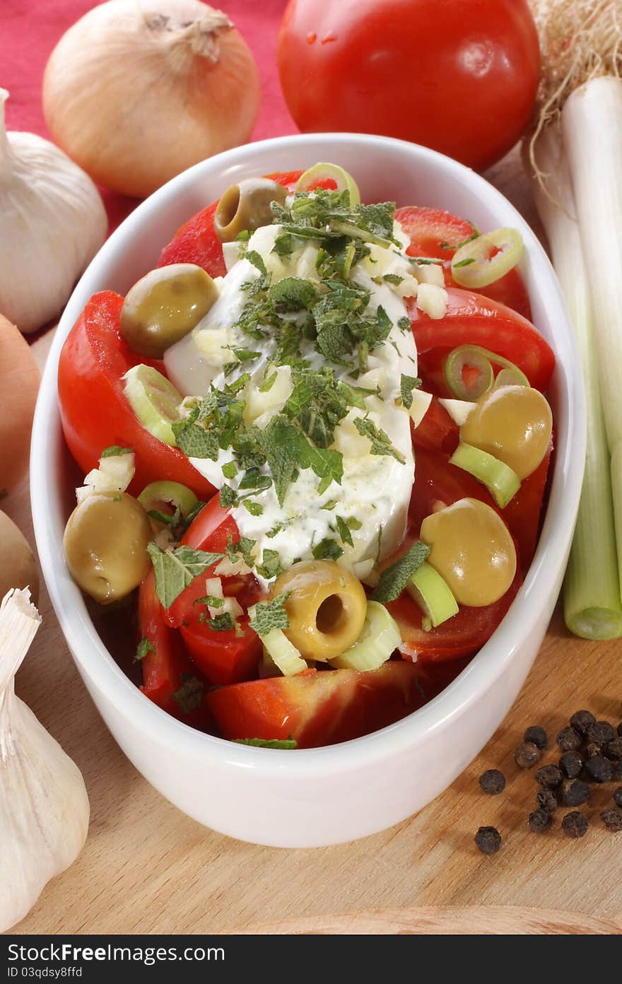 Mediterranean tomato salad with olives and garlic in a white bowl