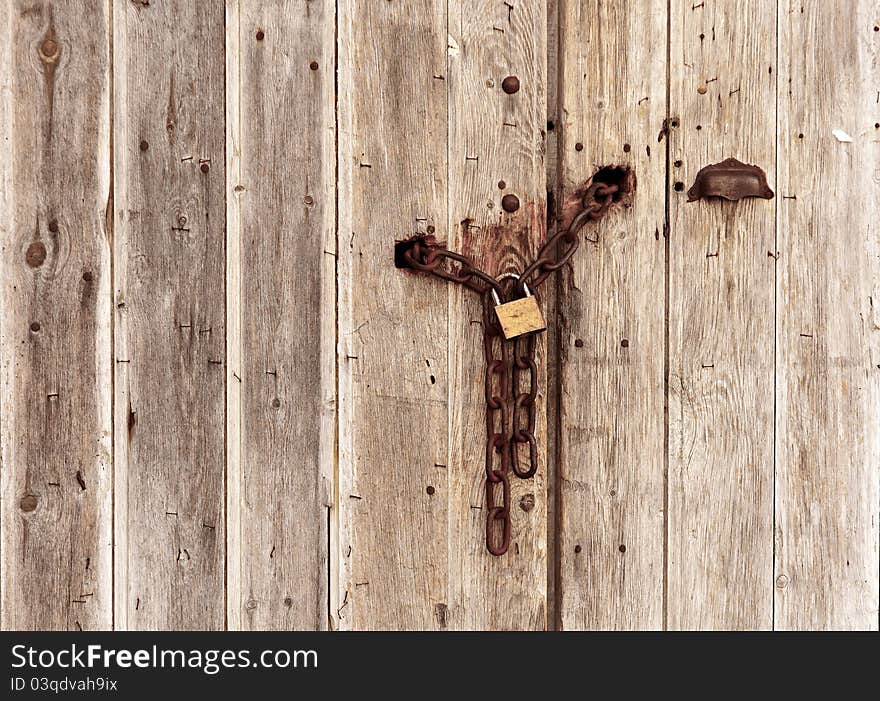 An old wooden door closed with a chain. An old wooden door closed with a chain