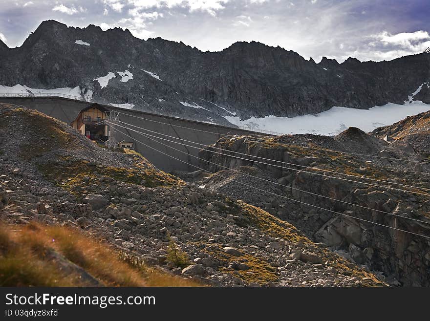 Dam and man-made lake between mountains. It’s Venerocolo Lake, North of Italy, Lombardy region, at 2.540 meters on the sea-level. In front the cableway. Dam and man-made lake between mountains. It’s Venerocolo Lake, North of Italy, Lombardy region, at 2.540 meters on the sea-level. In front the cableway