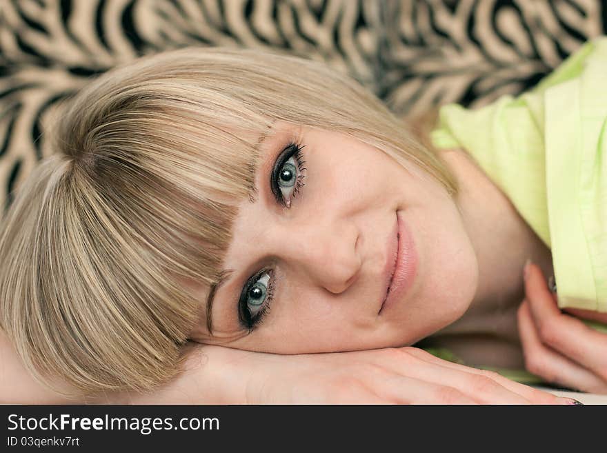 Girl's face lying on a sofa close up on a striped background. Girl's face lying on a sofa close up on a striped background