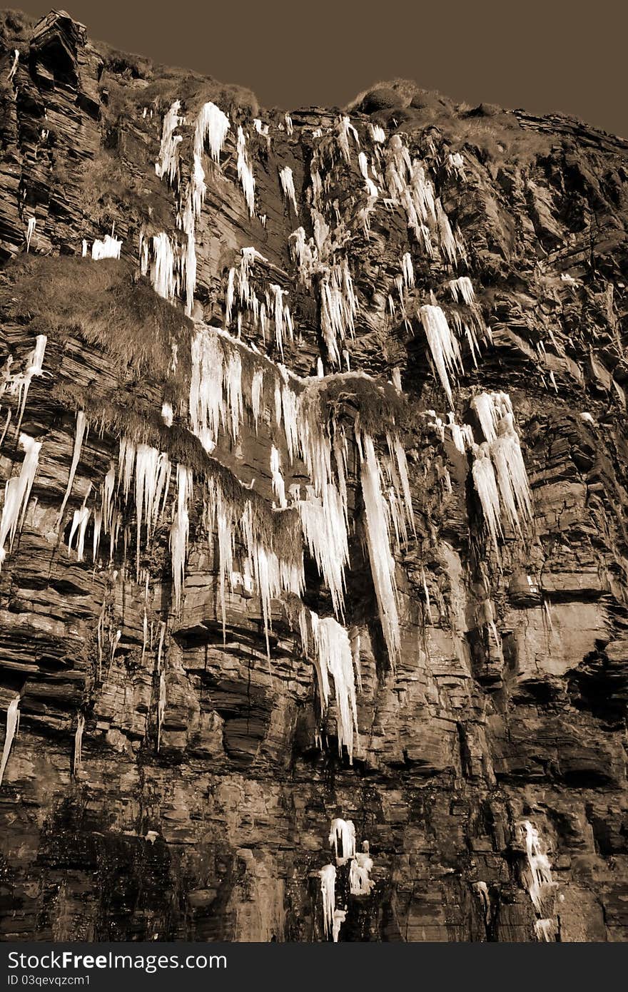 Cascade of icicles on a cliff face in sepia