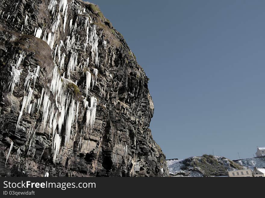 Cascade of icicles thaw on a cliff face