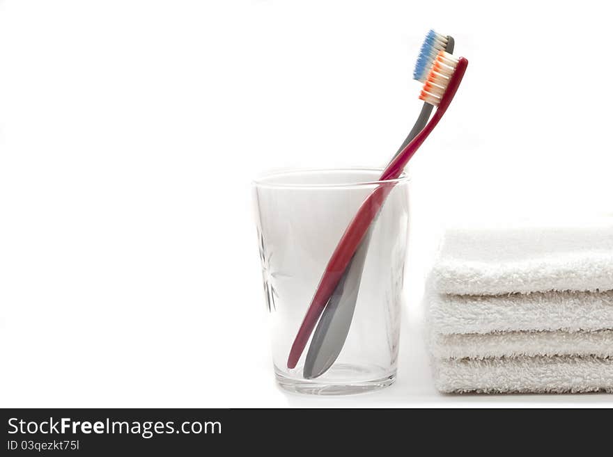 Two toothbrushs in a glass and towels