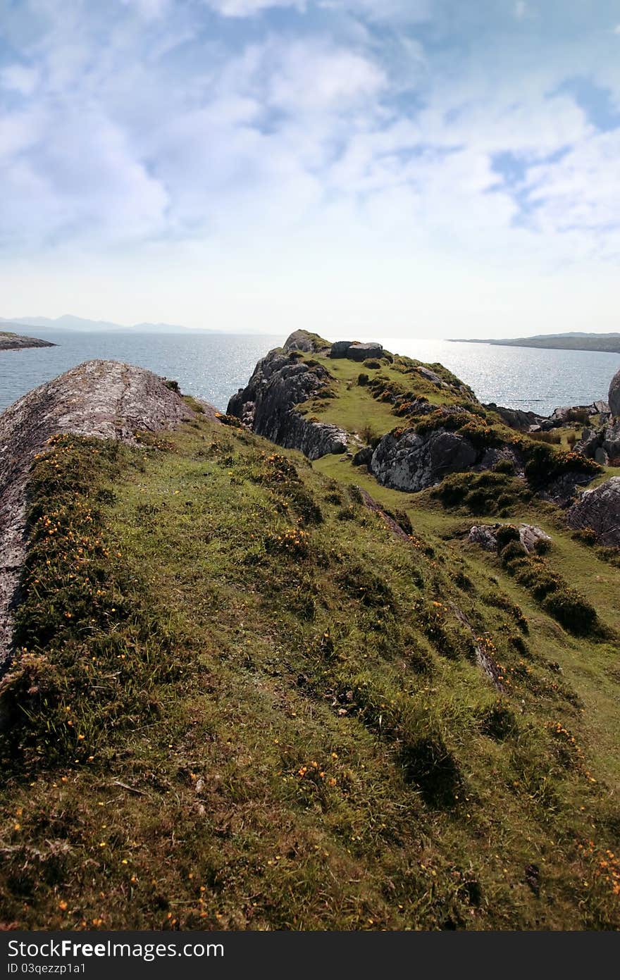 Scenic view in kerry ireland of rocks and sea with mountains against a beautiful bright sunny sky. Scenic view in kerry ireland of rocks and sea with mountains against a beautiful bright sunny sky