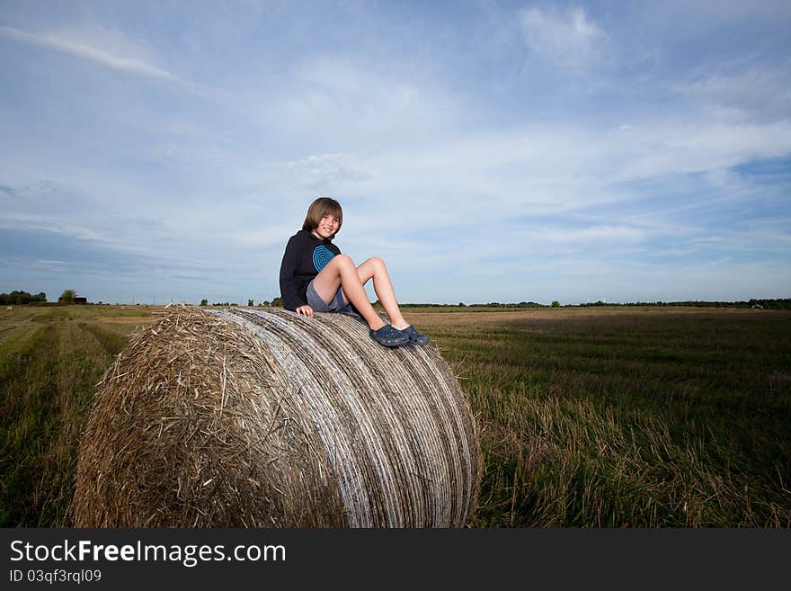 A boy sitting on huge bales of hay. A boy sitting on huge bales of hay