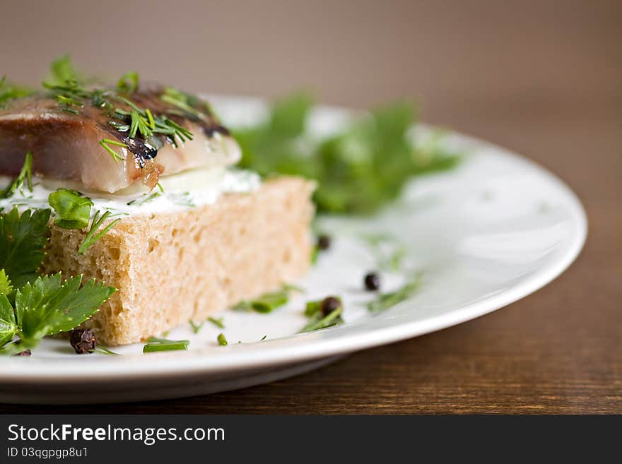 Sandwich with herring and white sauce on white plate