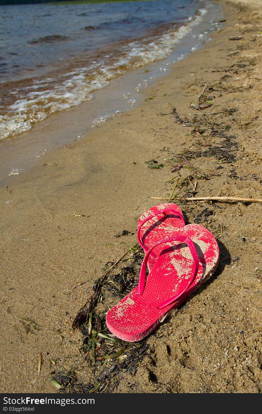 Red flip flops abandoned along a lakeside beach. Red flip flops abandoned along a lakeside beach