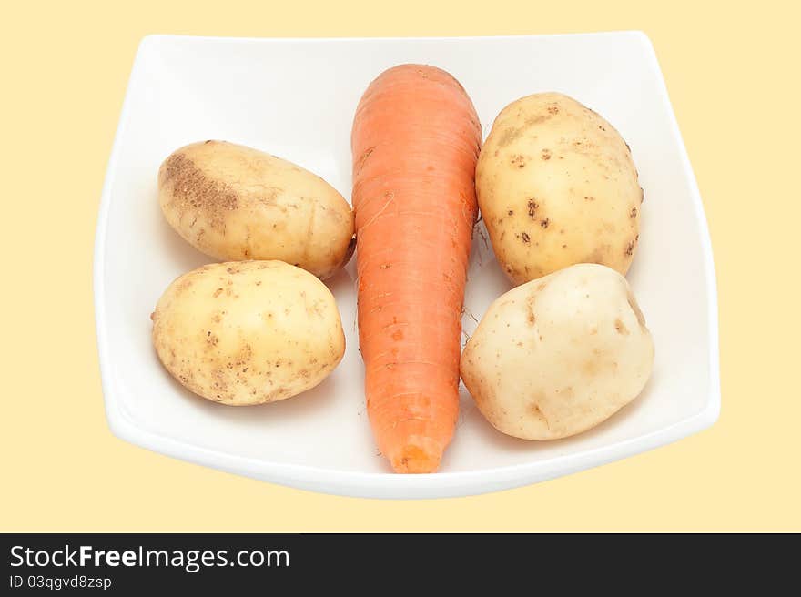 Carrots and potato on a white plate close up it is isolated