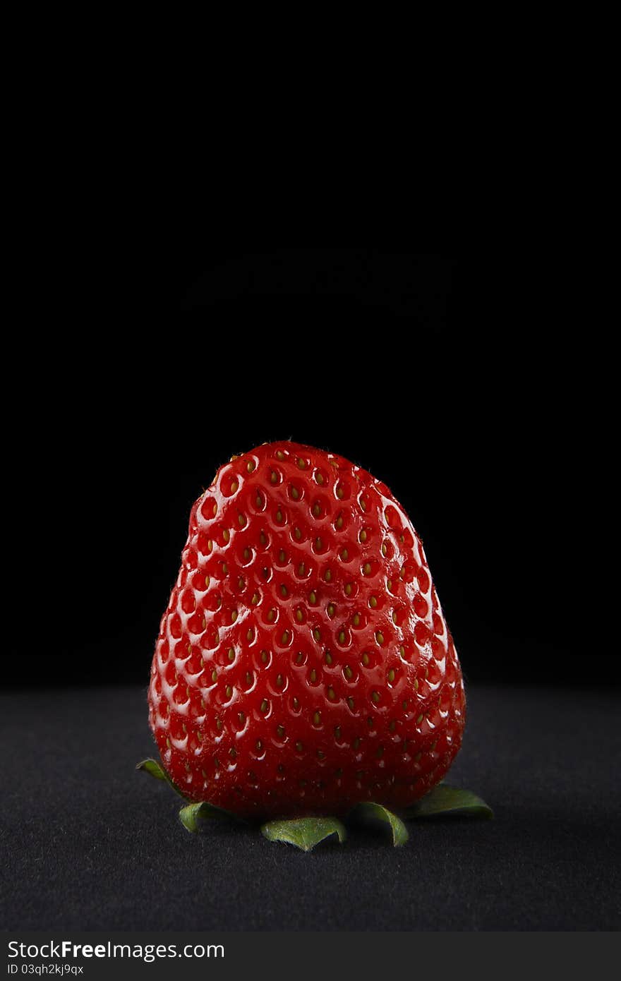 A perfect Strawberry on a black velvet background. A perfect Strawberry on a black velvet background.