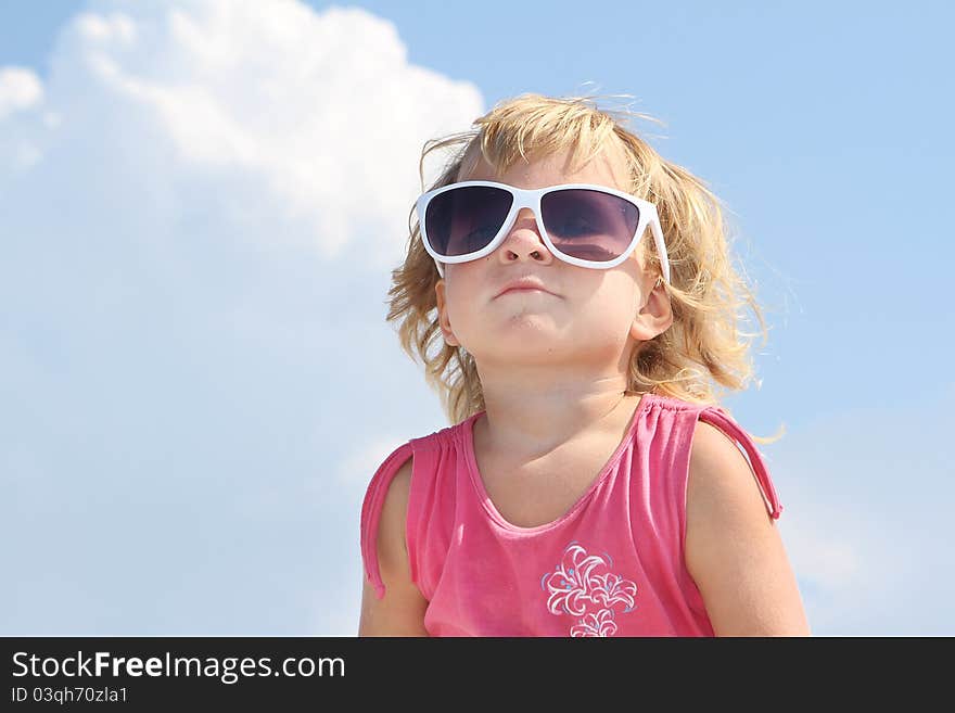 Cute young girl in sun glasses over sky background