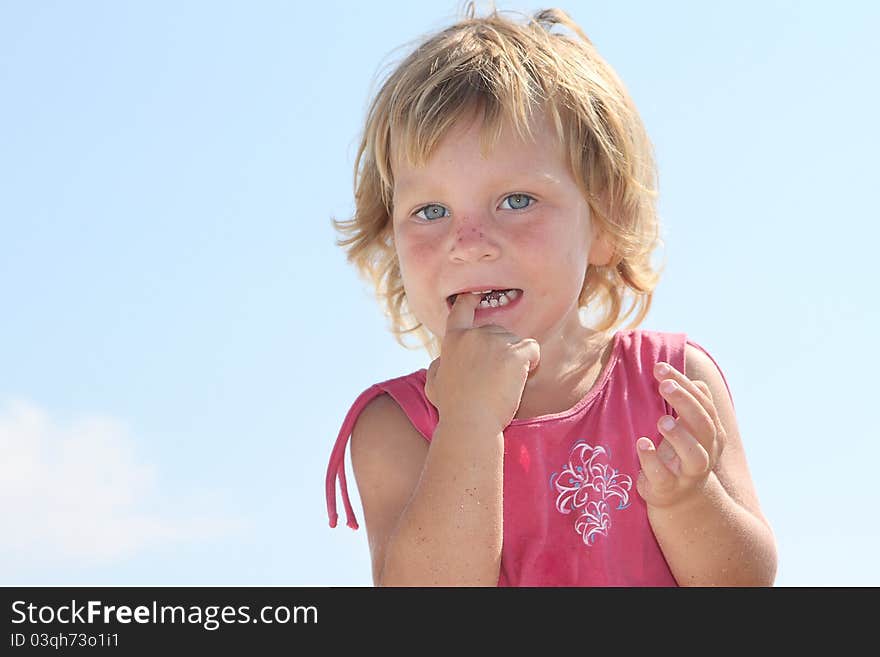 Cute young girl with finger in mouth over sky background