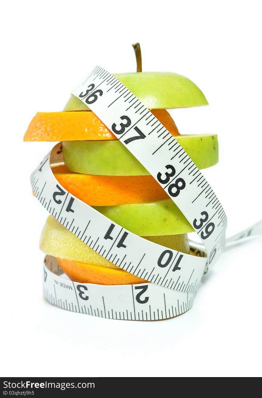 Tape measure wrapped around orange and apple slices. Tape measure wrapped around orange and apple slices