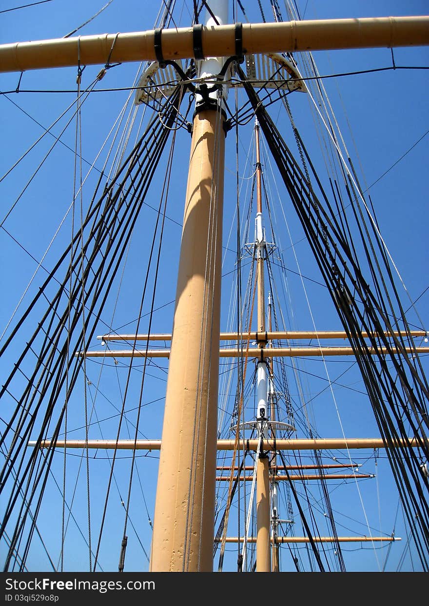 Closeup upshot of large sailboat mast and rigging set in front of a bright blue couldless sky. Closeup upshot of large sailboat mast and rigging set in front of a bright blue couldless sky.