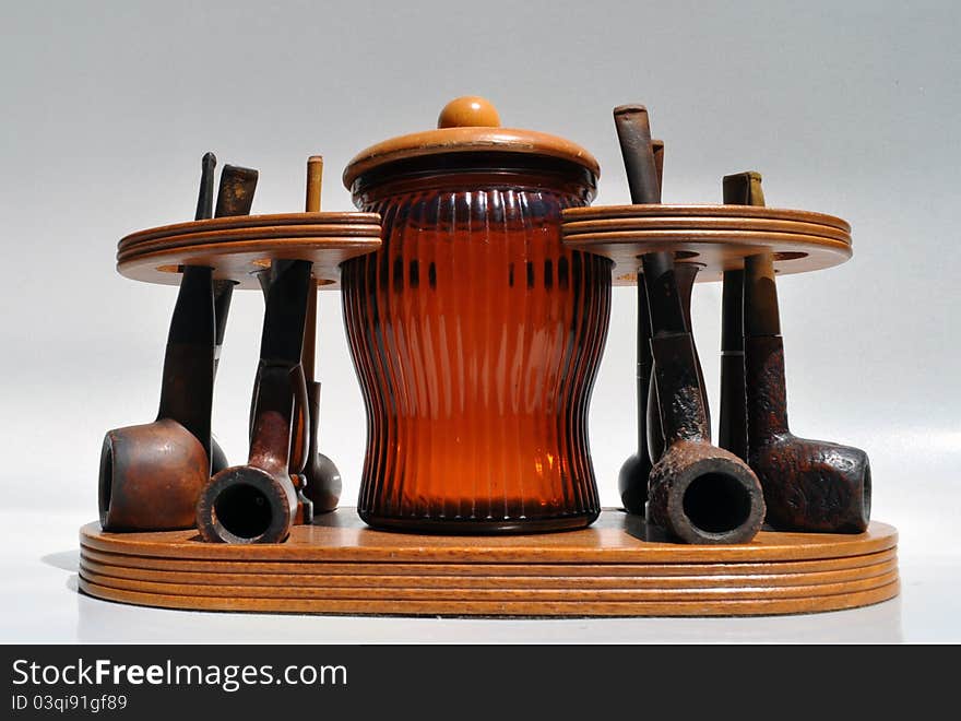 Vintage pipe collection in wood stand with brown glass tobacco jar / humidor. Vintage pipe collection in wood stand with brown glass tobacco jar / humidor