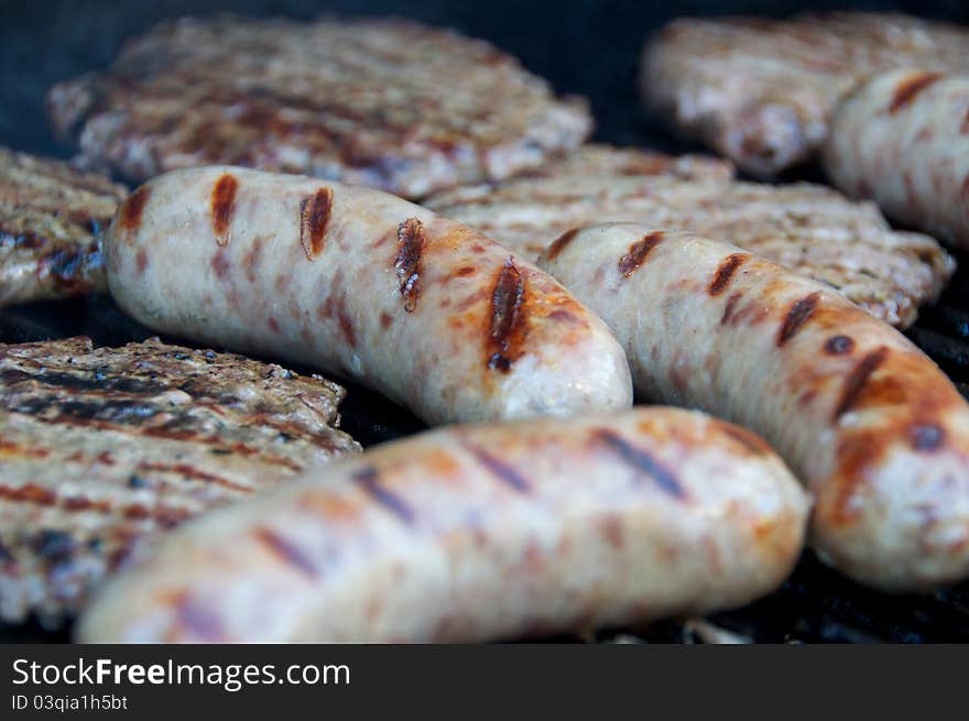 Bratwursts and hamburgers cooking on the grill. Bratwursts and hamburgers cooking on the grill.