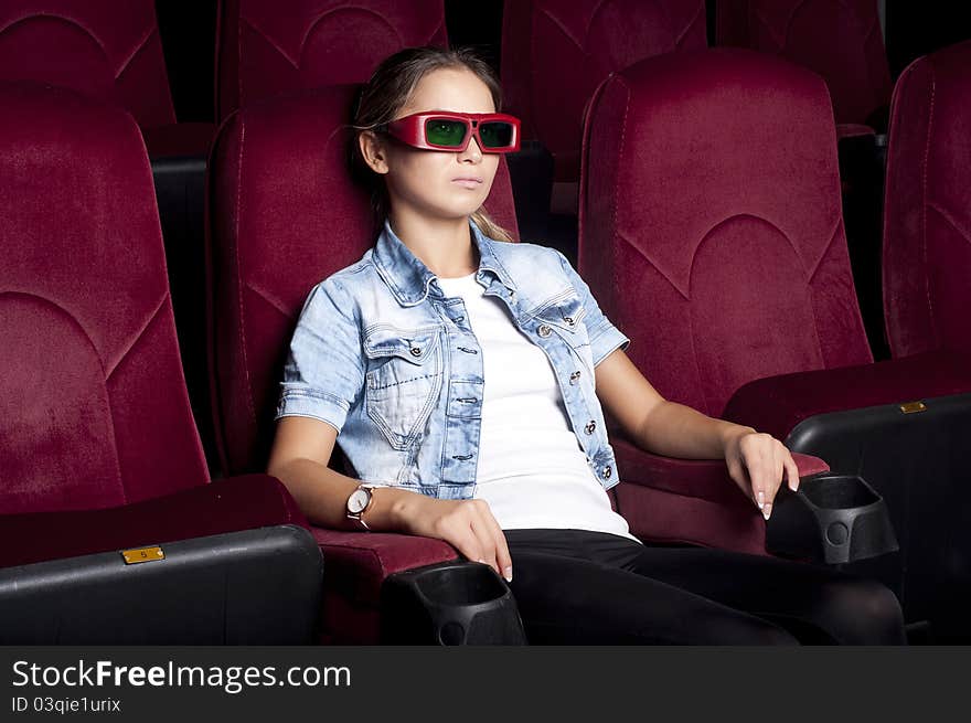 Young woman sitting alone in the cinema and watching a movie. Young woman sitting alone in the cinema and watching a movie