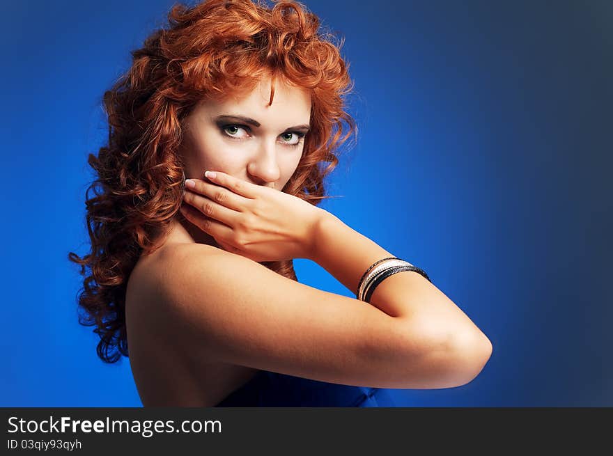 Portrait of young beautiful long-haired green-eyed redhead woman on blue background. Portrait of young beautiful long-haired green-eyed redhead woman on blue background