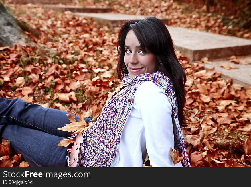 Beautiful smiling woman sitting in a park in autumn. Beautiful smiling woman sitting in a park in autumn