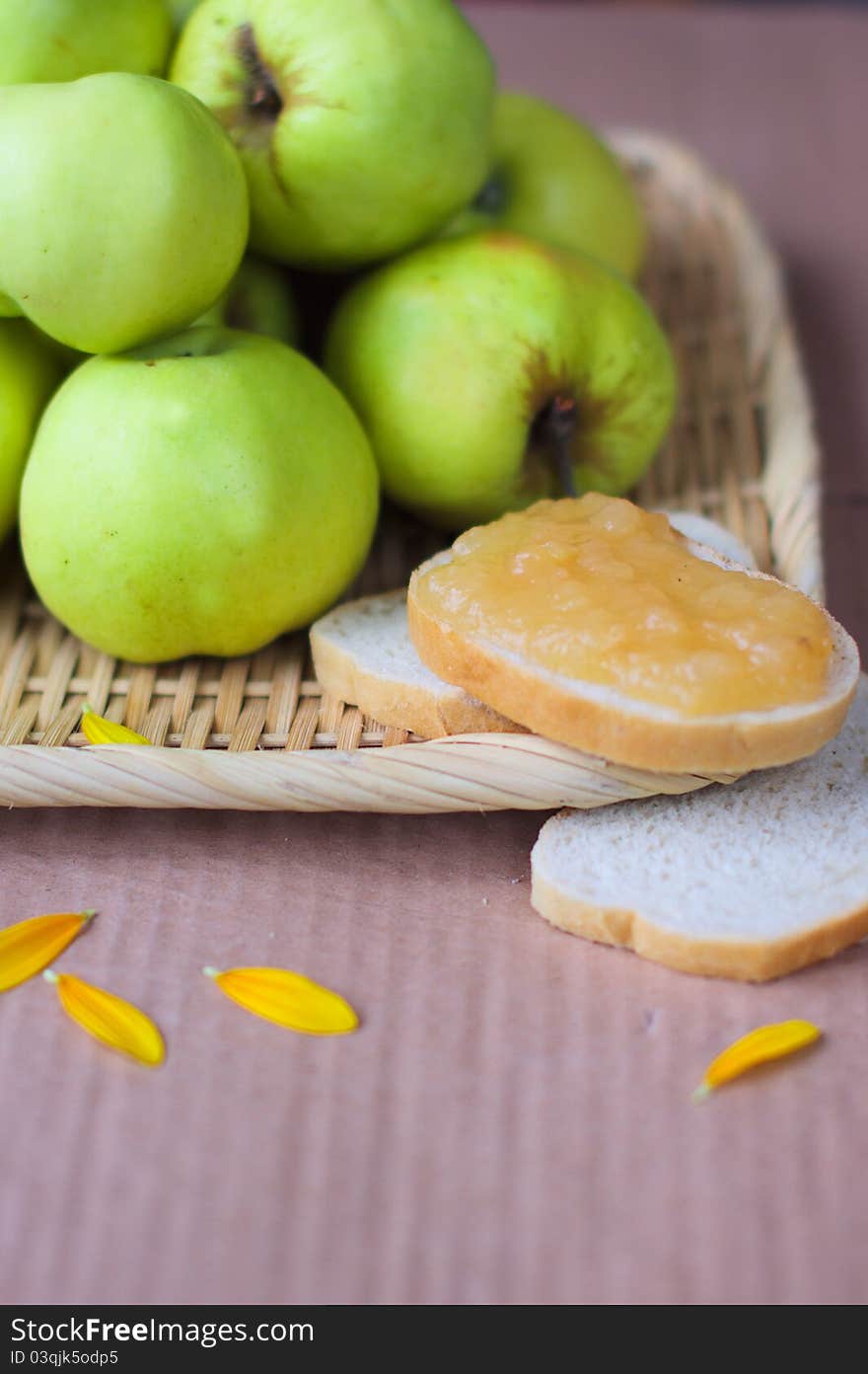 Green apple jam, bread, and the brown background with petals