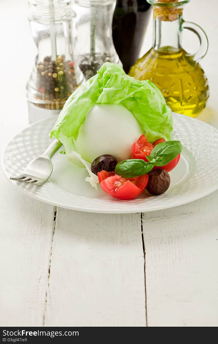 Delicious buffalo mozzarella with wrapped lettuce and tomatoes on wooden table