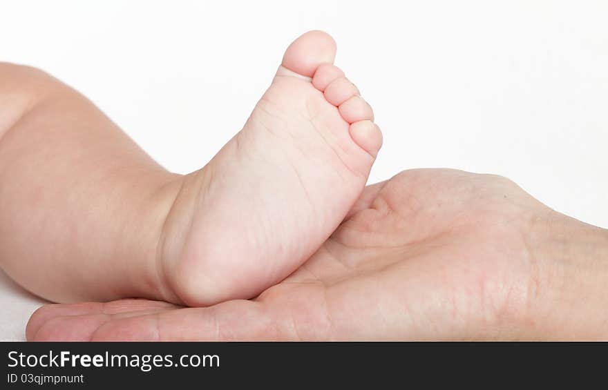 Baby foot in mother hands on white background