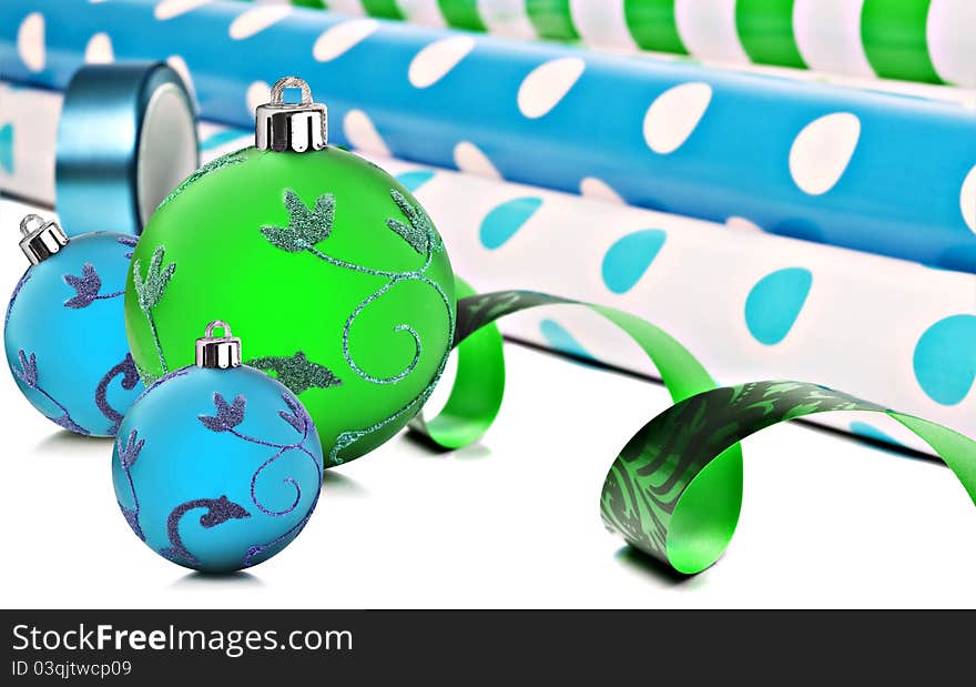 Rolls of gift wrapping paper and ribbon with blue and green christmas baubles. Rolls of gift wrapping paper and ribbon with blue and green christmas baubles