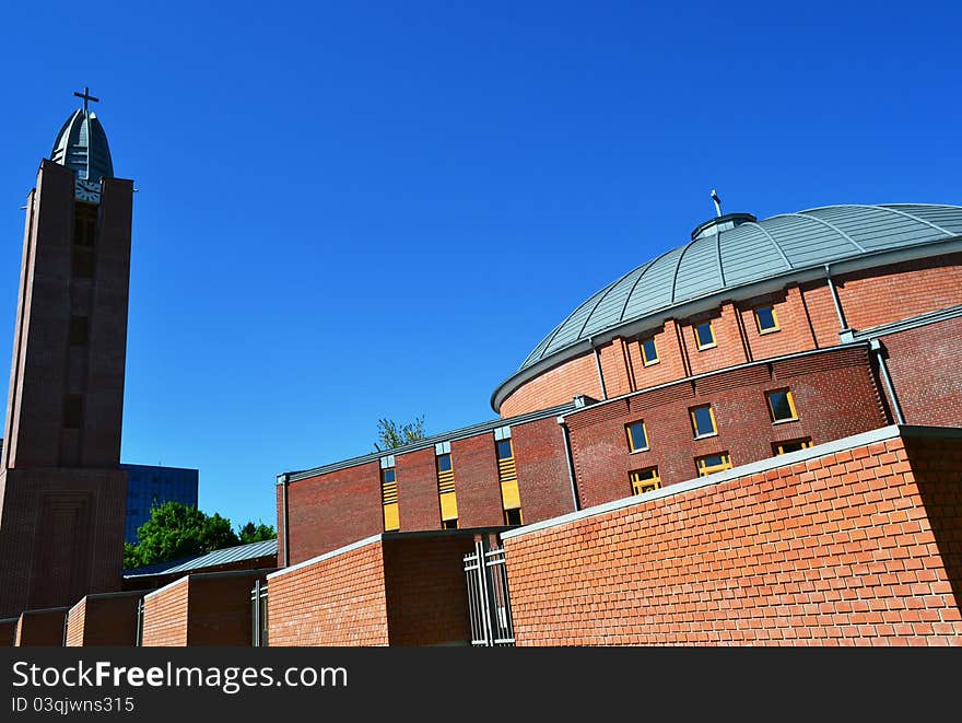 Perspective view of a modern church building with its belfry, cupola, windows and fencing.