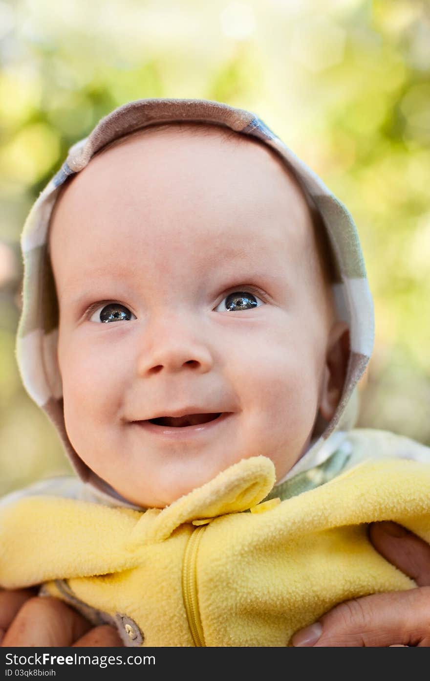 Happy baby boy on mother hands looking up