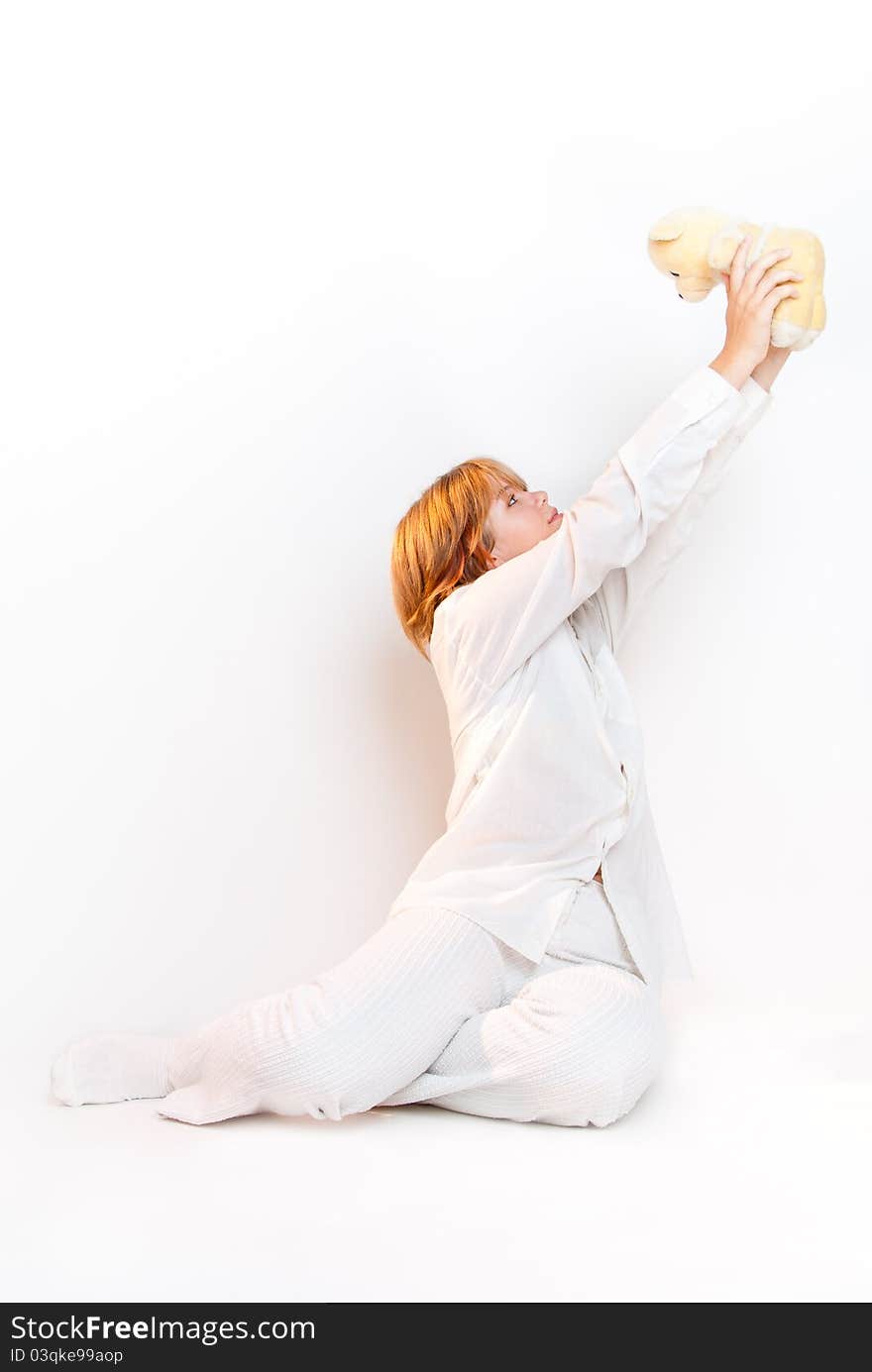 Girl in white looking at teddy bear overwhite