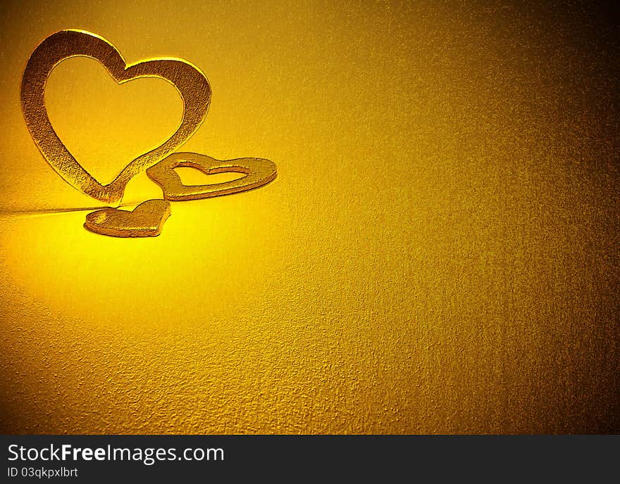 Three gold hearts on a gold background. Three gold hearts on a gold background.