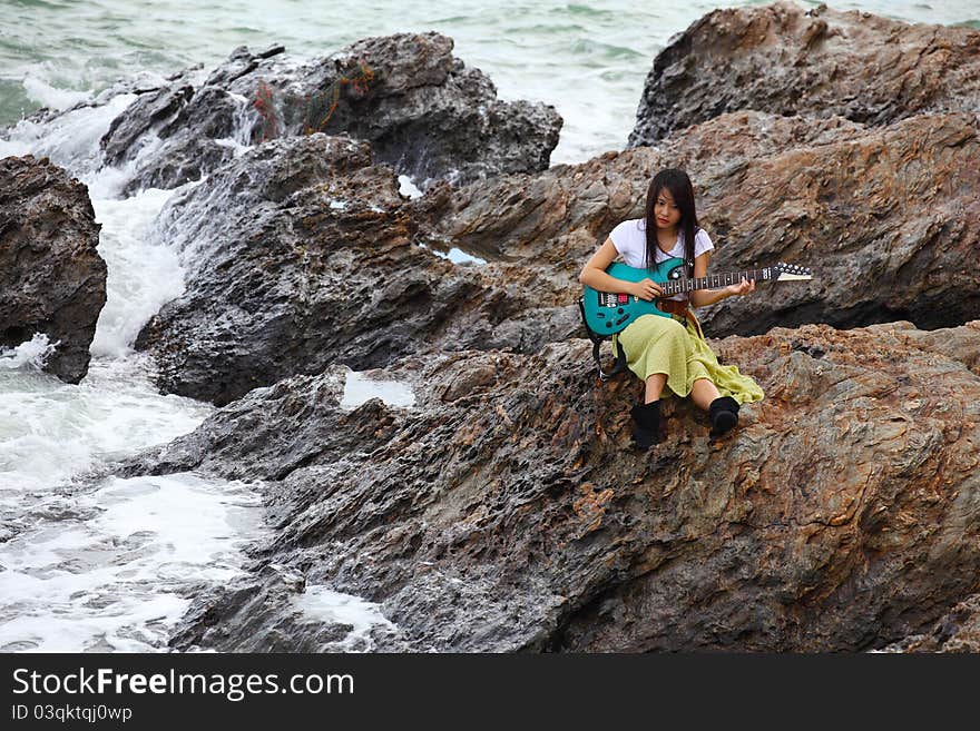 Beautiful asian woman with a guitar on beach