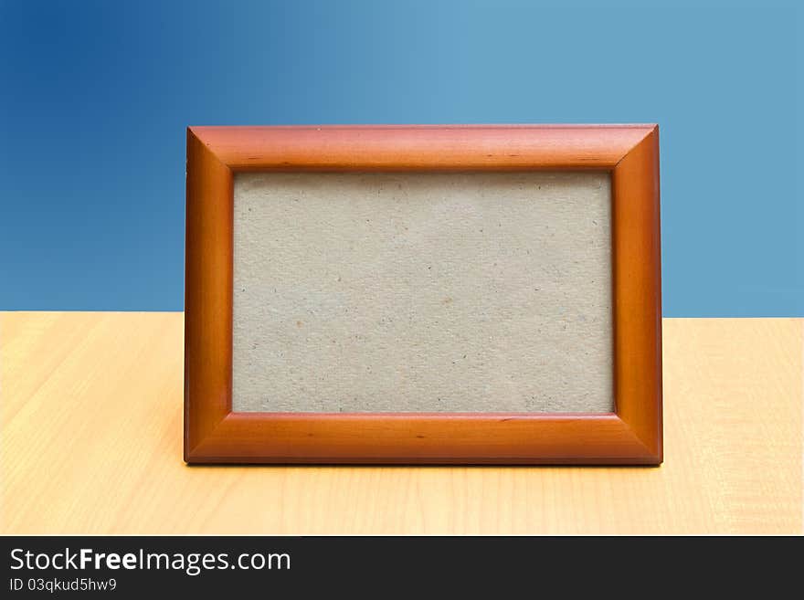 Frame on a wooden table and a blue backdrop